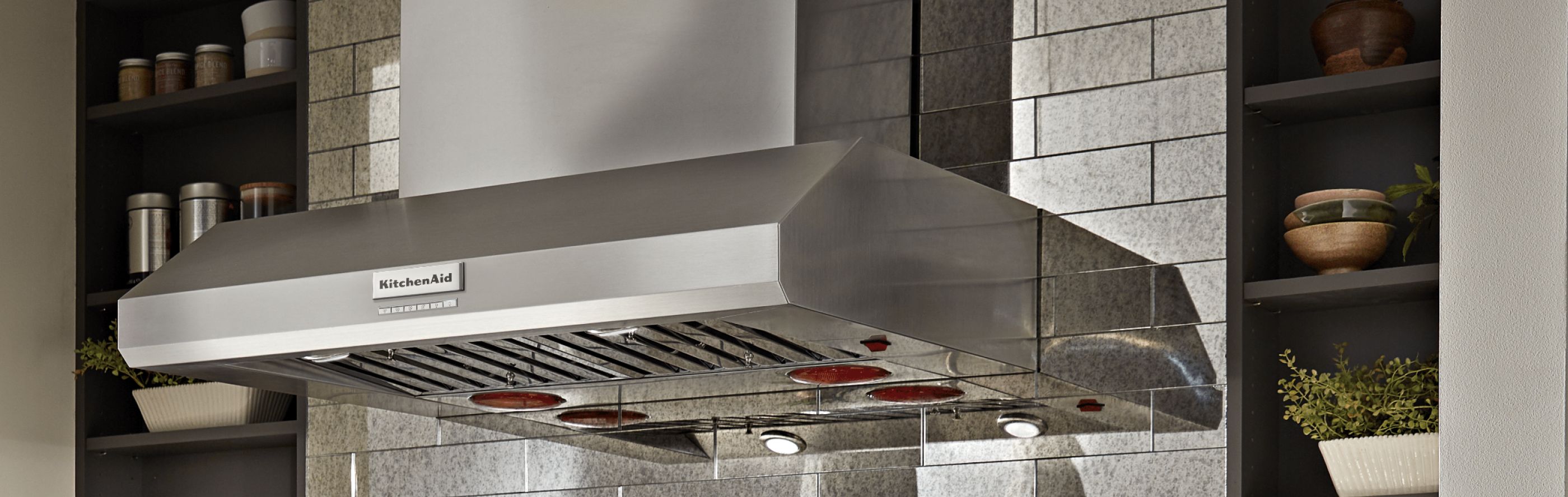 A KitchenAid® range hood against a backdrop of kitchen cabinets
