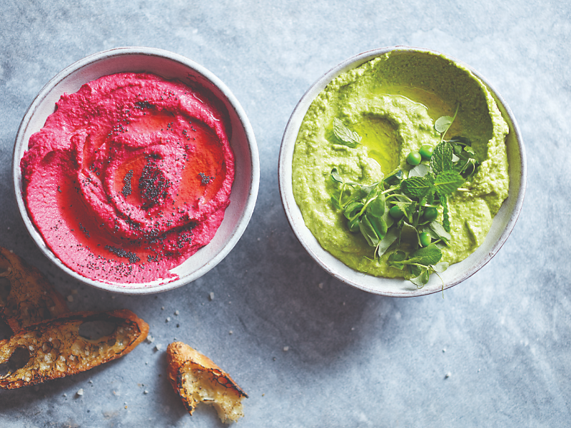 Pink and green hummus topped with fresh herbs