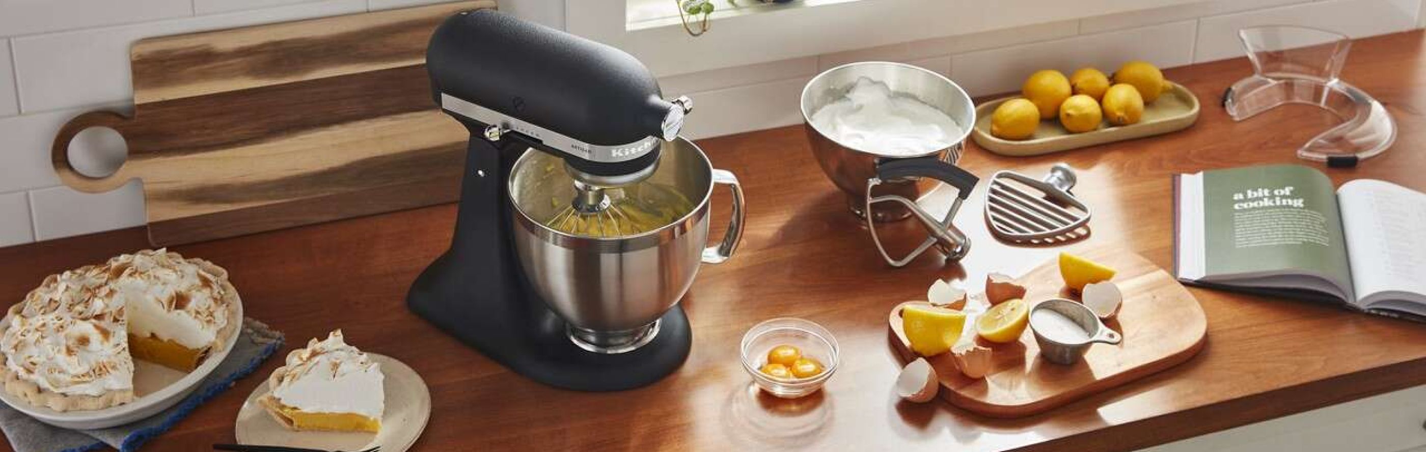 Black KitchenAid® stand mixer on countertop with various ingredients and slice of pie