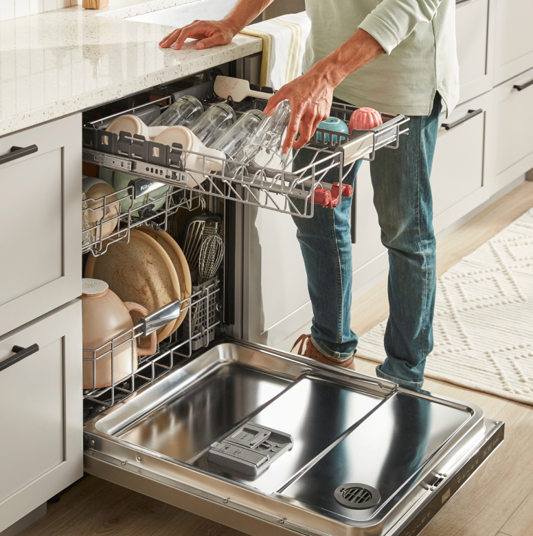 Man loading glasses in third rack of dishwasher