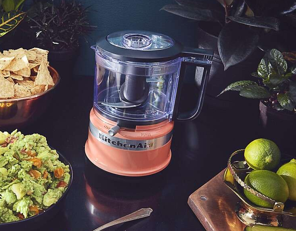 Coral food chopper next to bowl of guacamole and limes