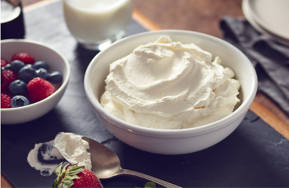 A bowl of whipped cream next to a bowl of berries A bowl of whipped cream next to a bowl of berries