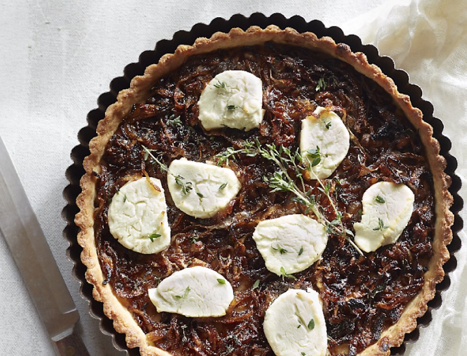 Caramelized onion goat cheese tart on table next to knife Caramelized onion goat cheese tart on table next to knife
