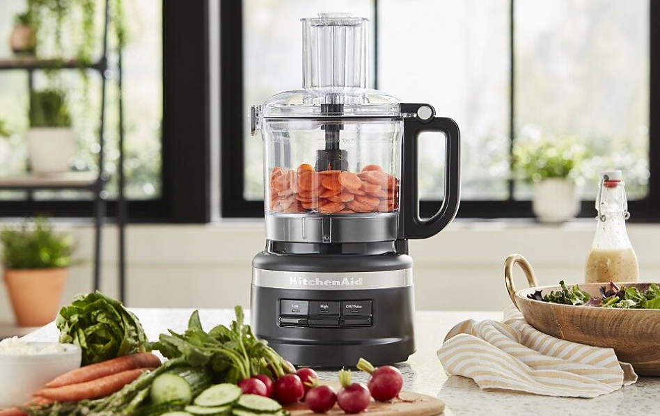 Black KitchenAid® food processor with sliced carrots and vegetables in bright kitchen
