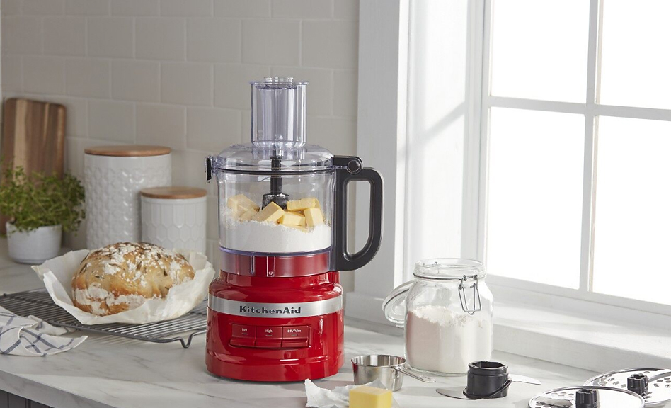 Red food processor with butter and flour next to a loaf of bread