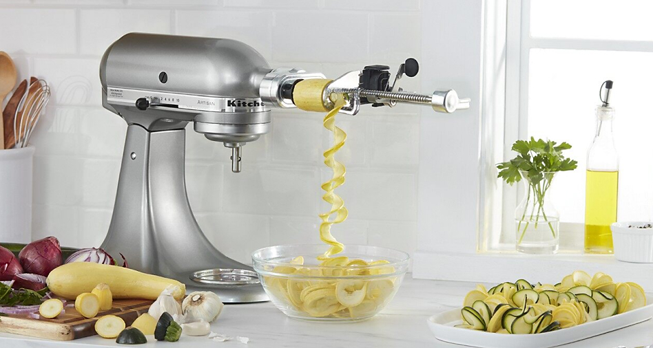 Silver KitchenAid brand stand mixer with zucchini in the spiralizing attachment