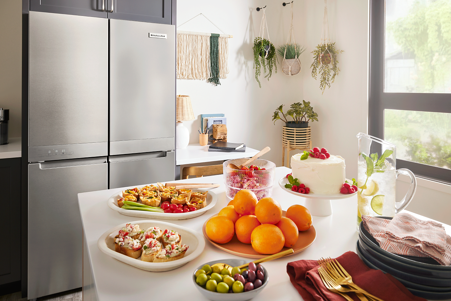KitchenAid® four-door refrigerator across from an island counter with serving dishes full of food
