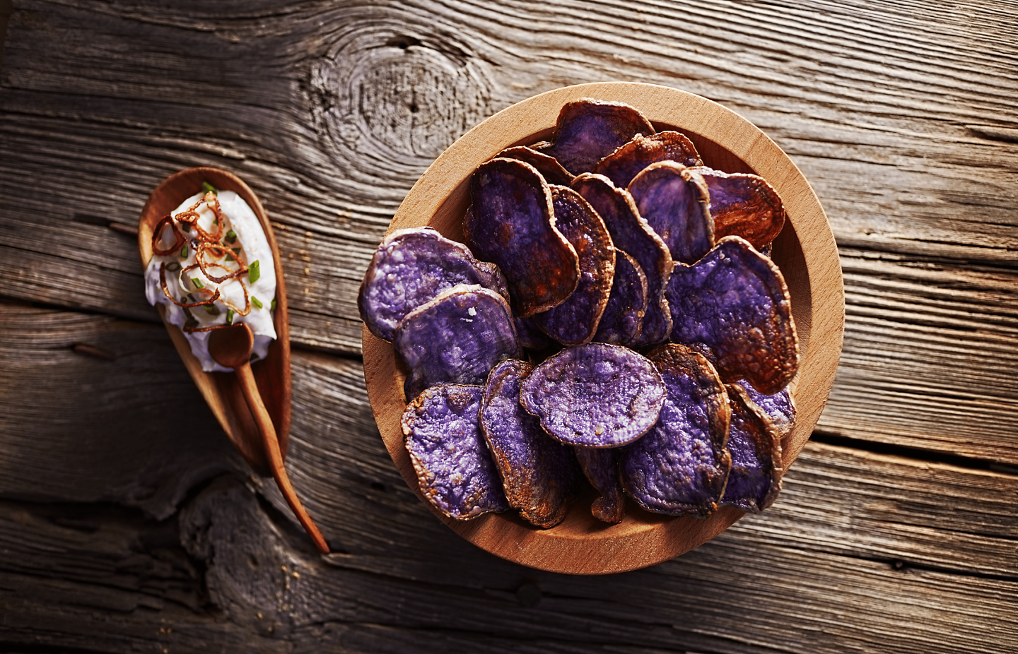 Purple parmesan potato chips with dip on a wooden table