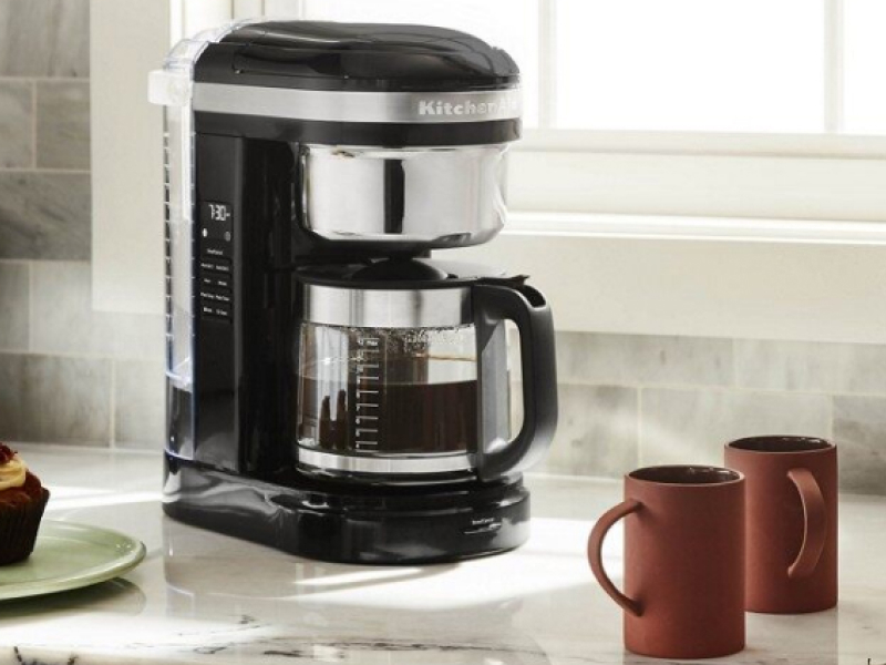 KitchenAid® 12 Cup Drip Coffee Maker full of coffee on counter with mugs
