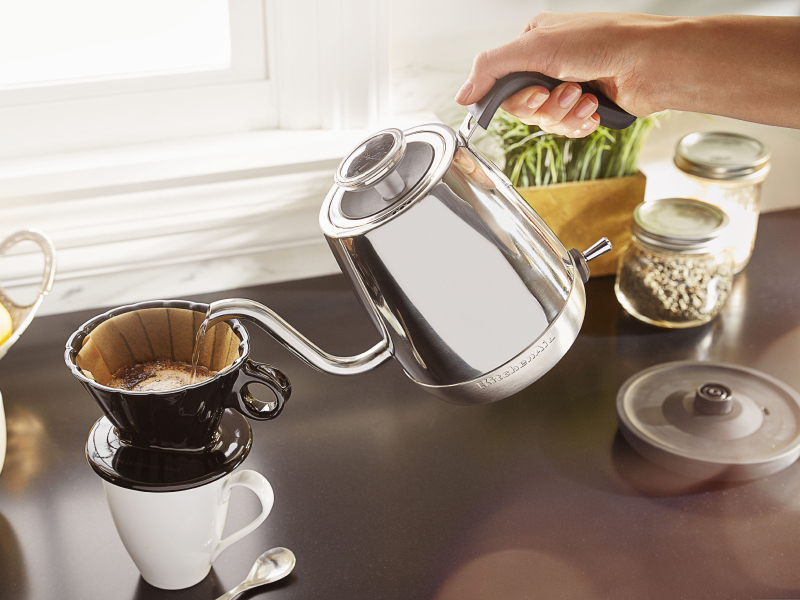 Person pouring hot water with silver KitchenAid® electric kettle
