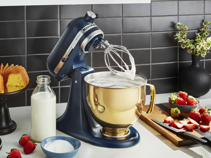 Blue KitchenAid® stand mixer with gold mixing bowl and wire whisk attachment