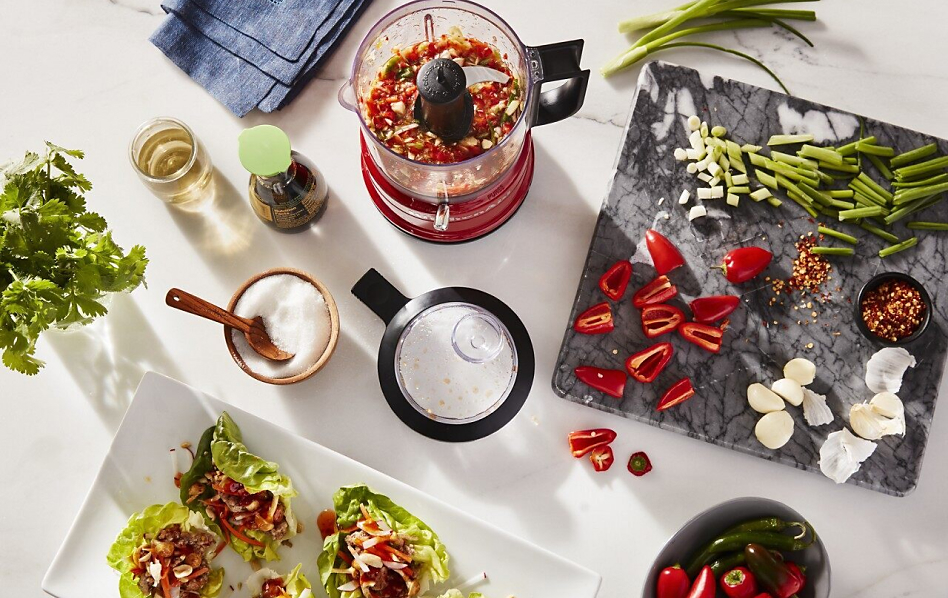 View of red KitchenAid® food processor on white counter with salsa ingredients