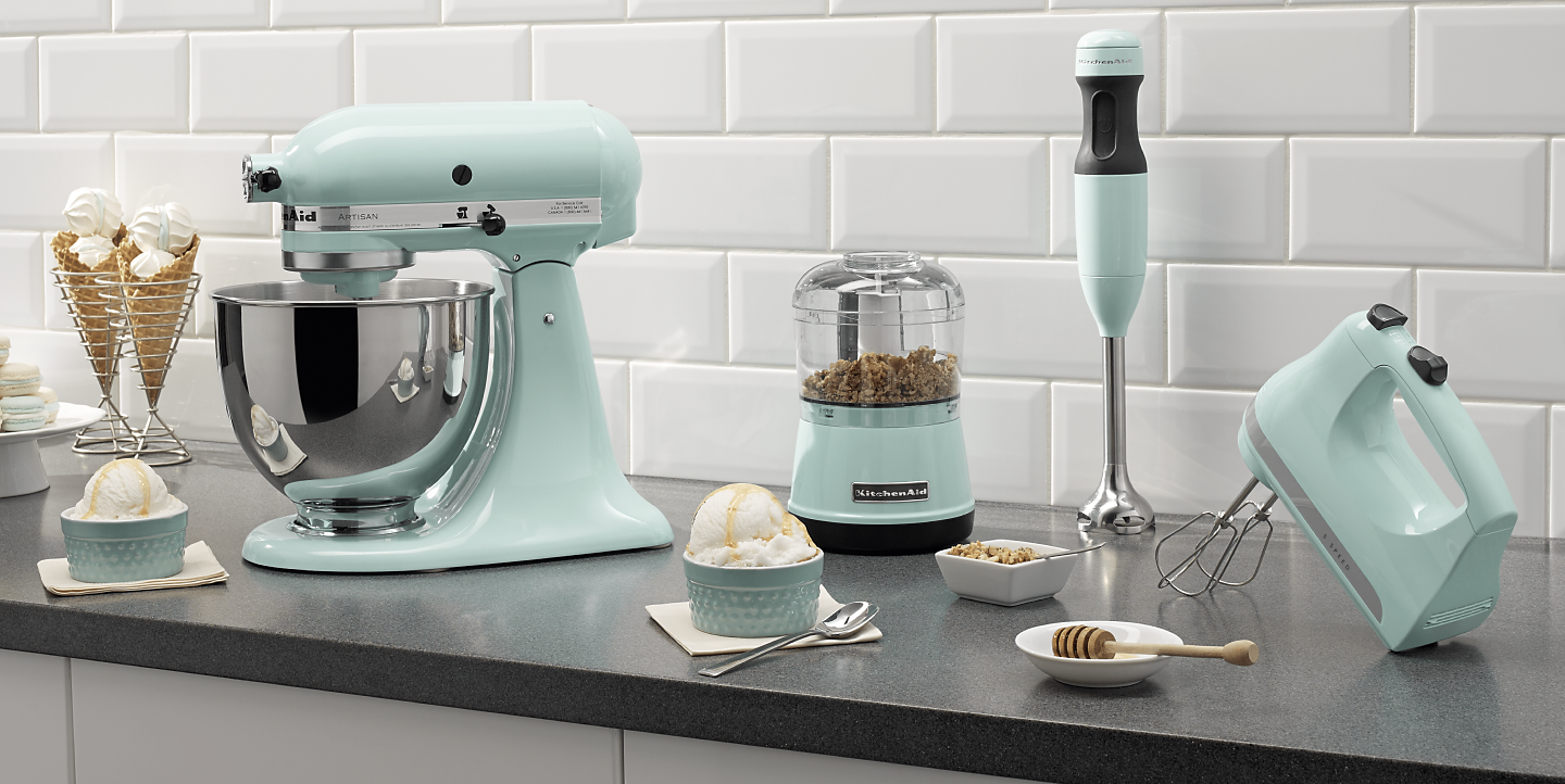  Mint green KitchenAid® food processor, stand mixer, hand mixer and immersion blender on countertop with ingredients