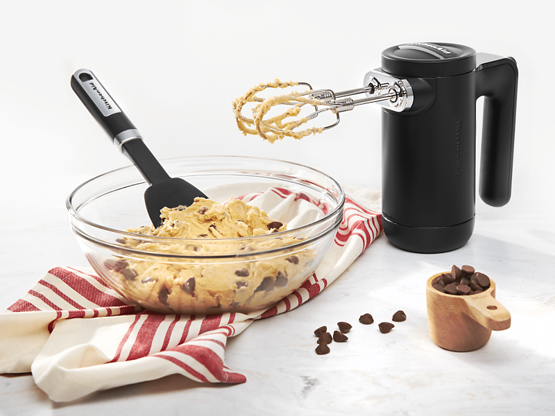 Black KitchenAid® hand mixer with bowl of chocolate chip cookie dough