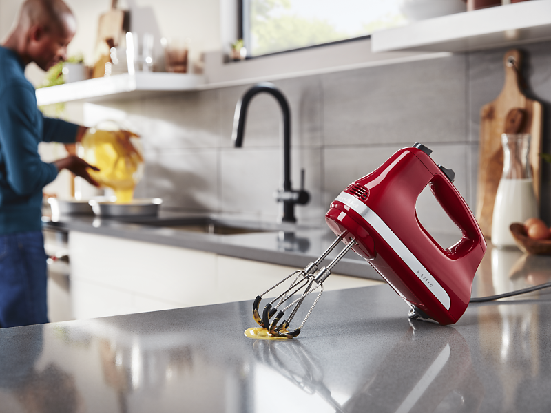 Red KitchenAid® hand blender with flex beater accessory on countertop