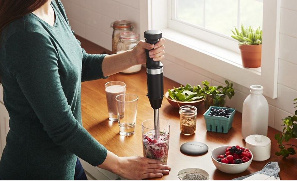 Woman blending smoothie with black KitchenAid® cordless immersion blender