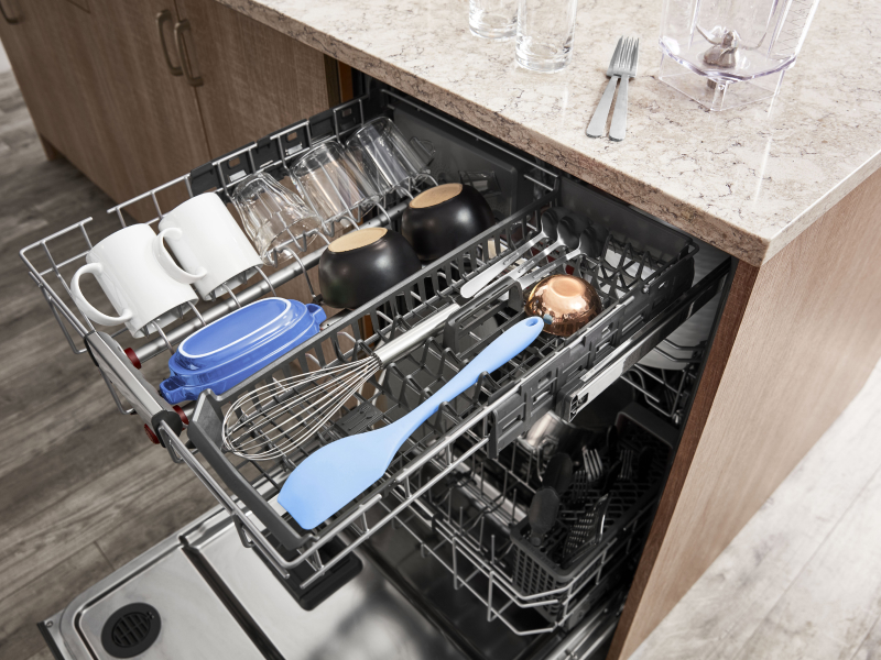 The top rack of a KitchenAid® dishwasher with utensils and glassware.
