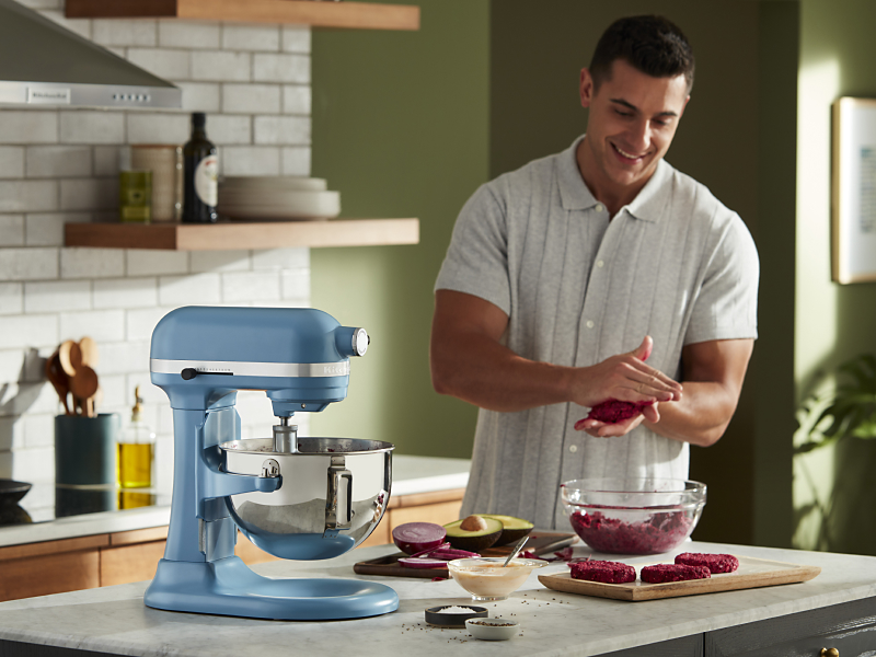 A man flattening patties next to a blue bowl-lift KitchenAid® stand mixer