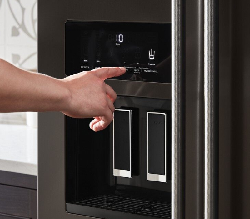 Finger touching the control pad of a refrigerator water dispenser