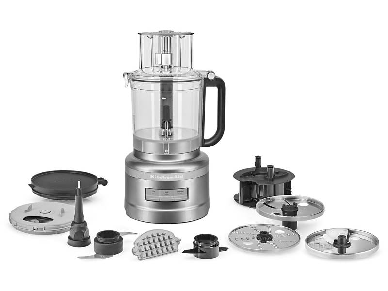 A food processor with its attachments displayed in front it.