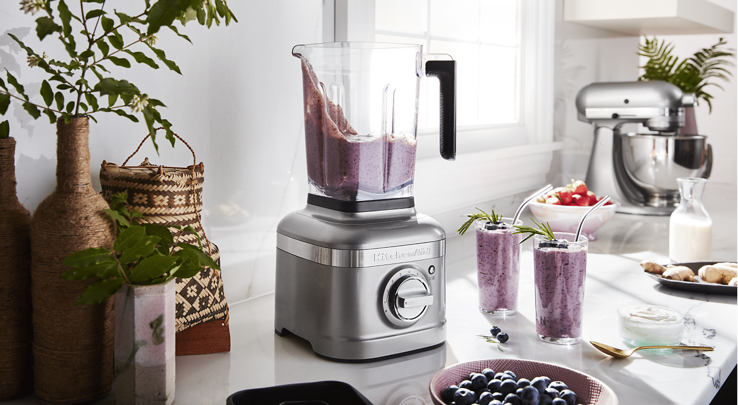Silver KitchenAid® blender with smoothie next to two glasses of smoothie