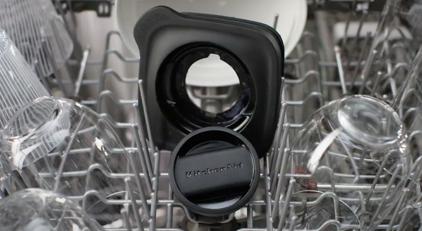 Black KitchenAid® blender lid and top on dishwasher rack
