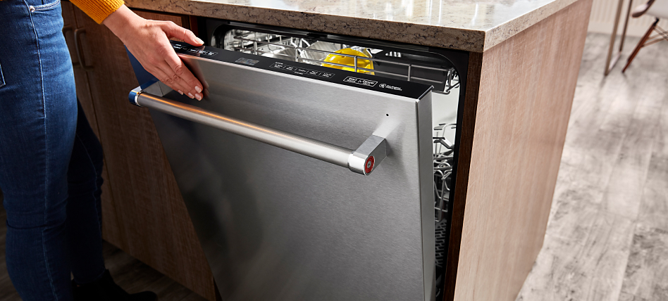Close-up of hand closing KitchenAid® dishwasher. 