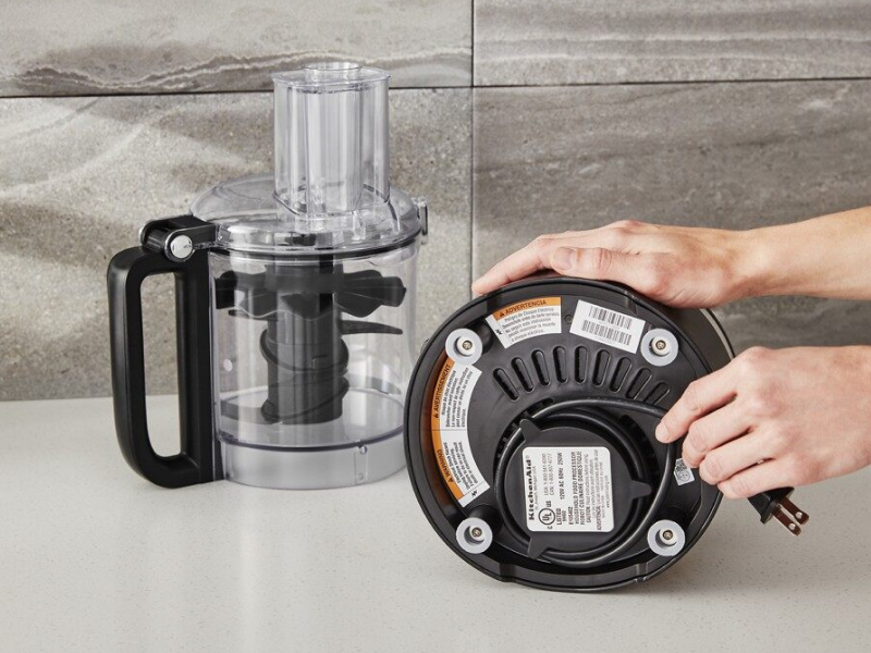 A person holding the power cord of a disassembled food processor