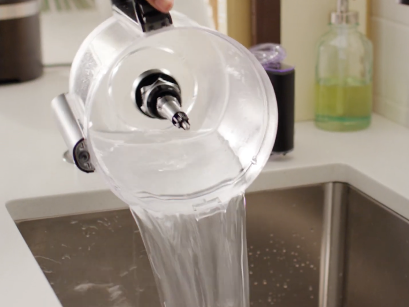 A person cleaning the bowl of a disassembled food processor