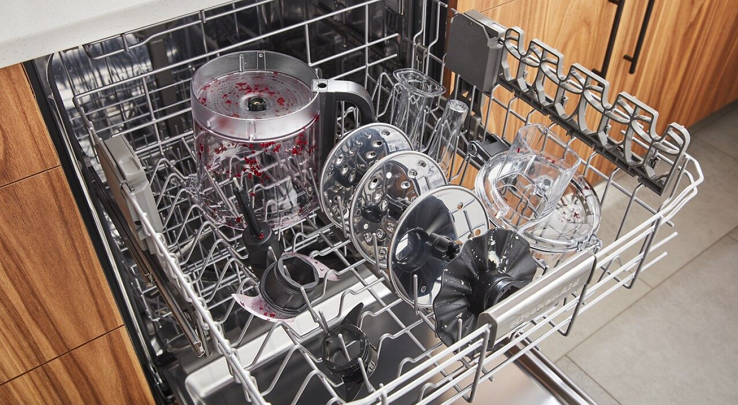 Parts of a disassembled food processor loaded in a dishwasher