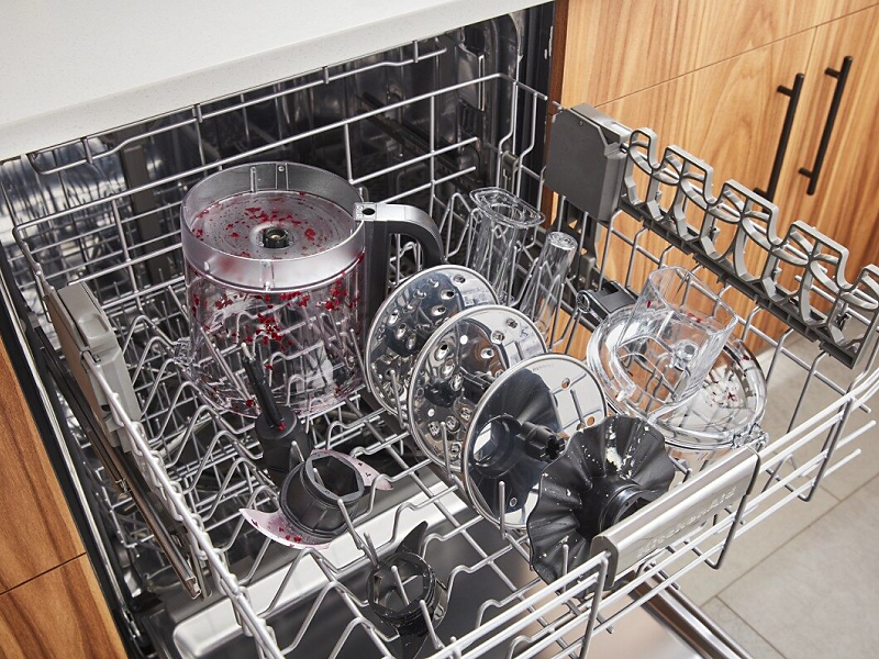 Parts of a disassembled food processor loaded in a dishwasher