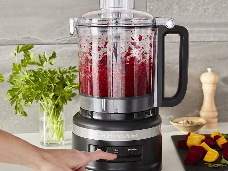 A person using a KitchenAid® food processor to process fresh ingredients