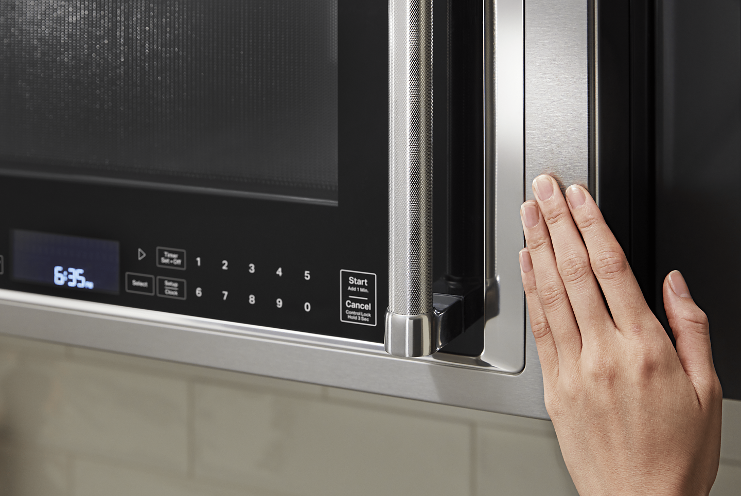 Hand closing a KitchenAid® over the range microwave