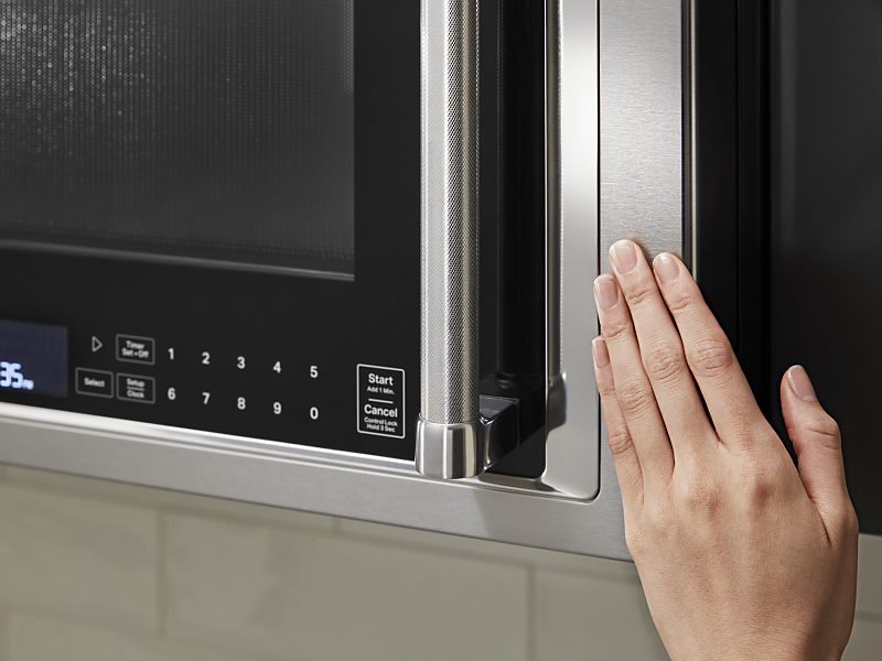 Hand closing a KitchenAid® over the range microwave