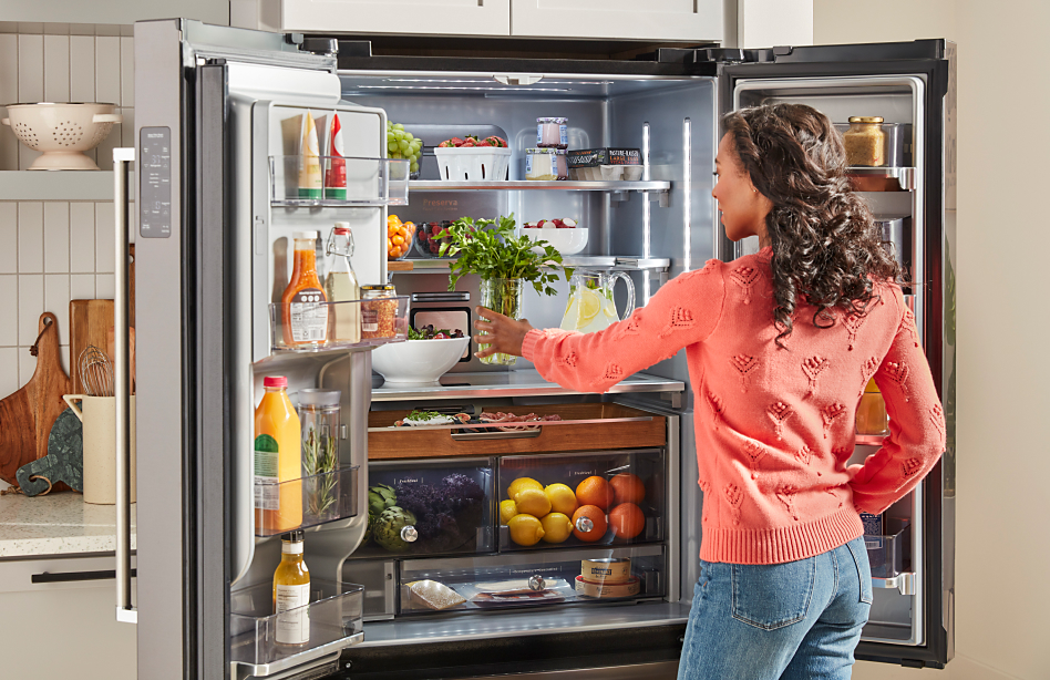 Woman taking food out of an open French door refrigerator 