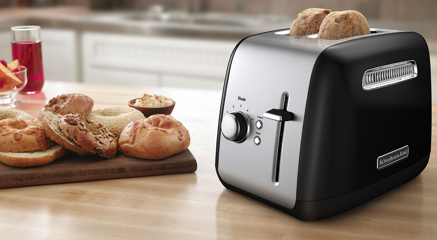 Bagel slices in a silver KitchenAid® toaster on a modern kitchen counter.