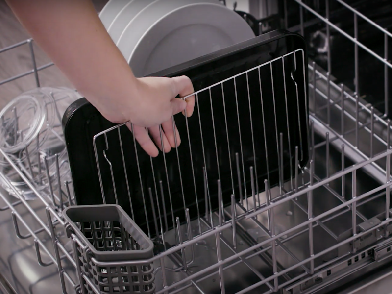 A person pulling an air fryer rack out of a dishwasher