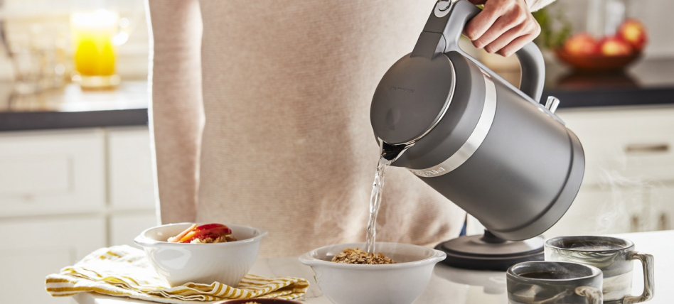 Person pouring hot water into a bowl of grains from a KitchenAid® electric kettle