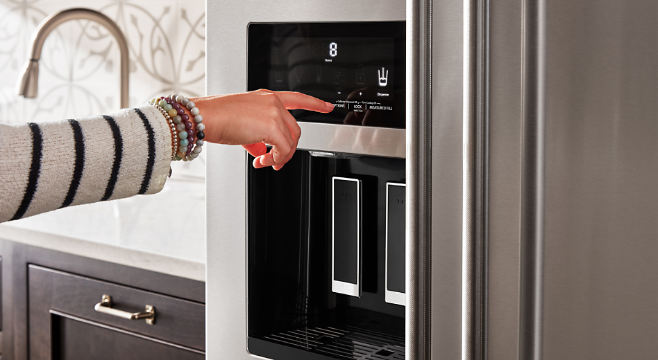 Person pressing the ice dispenser button on a refrigerator 