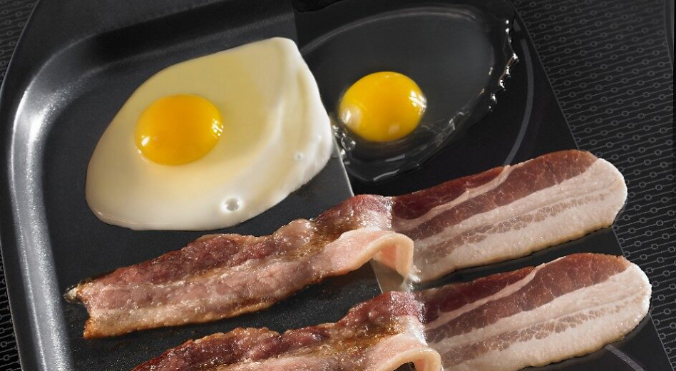 Bacon and eggs sizzling on an induction cooktop.