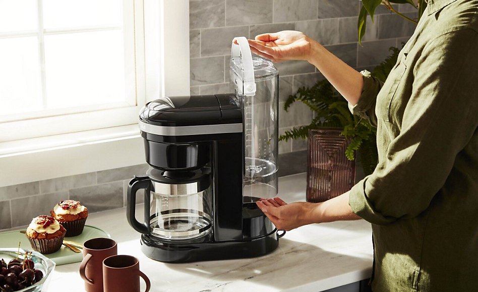 Woman replacing water tank in espresso machine