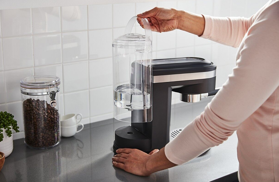 Hand removing the water tank of a KitchenAid® espresso machine.