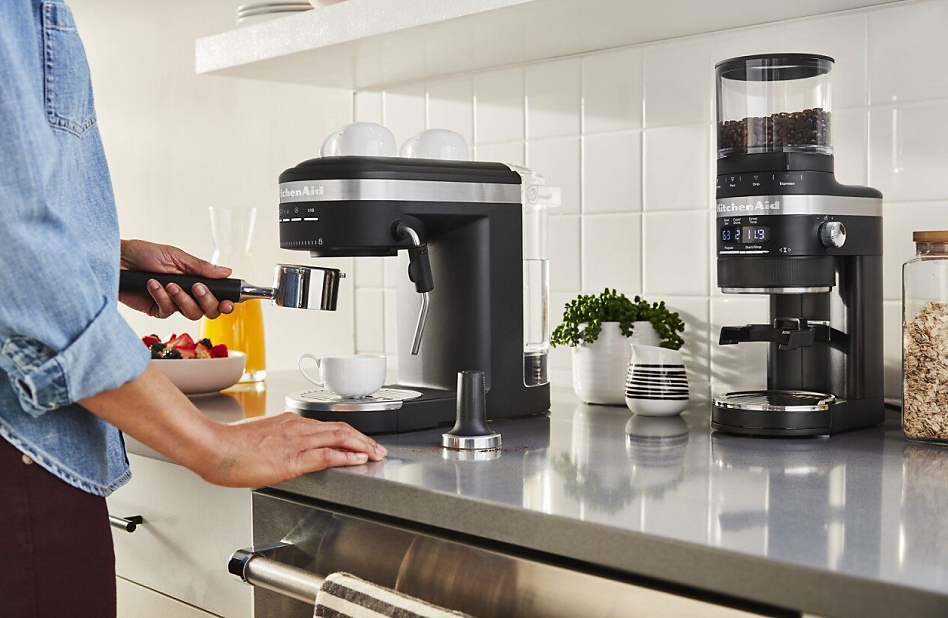 Hand inserting portafilter into group head of KitchenAid® espresso machine.
