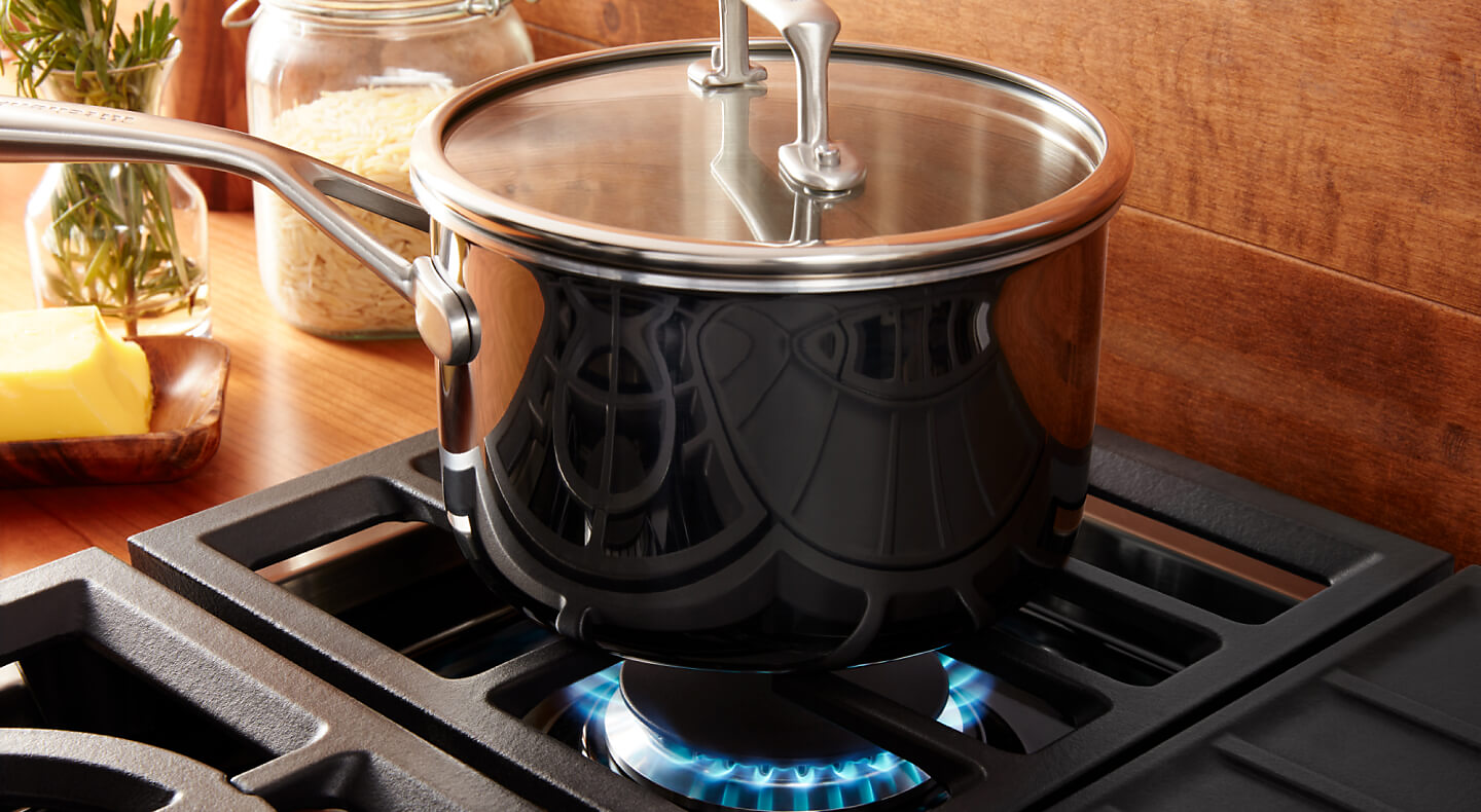 Pot cooking over a gas range against a wooden backsplash. 