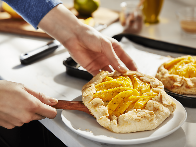Hands placing homemade apple galette on a plate