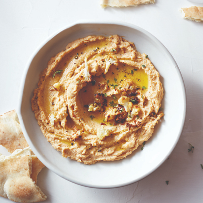 Bowl of hummus topped with herbs and olive oil