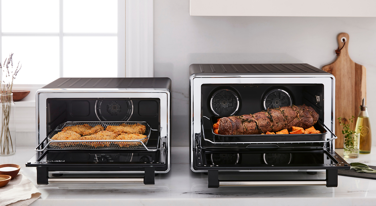 Two KitchenAid® countertop ovens with freshly prepared food on a modern kitchen counter.