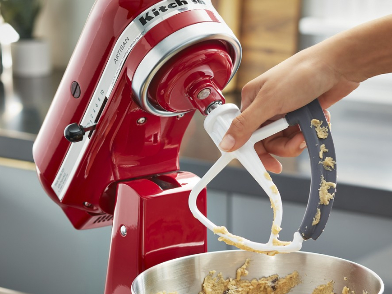 Person removing a KitchenAid® flex edge beater accessory from a red stand mixer