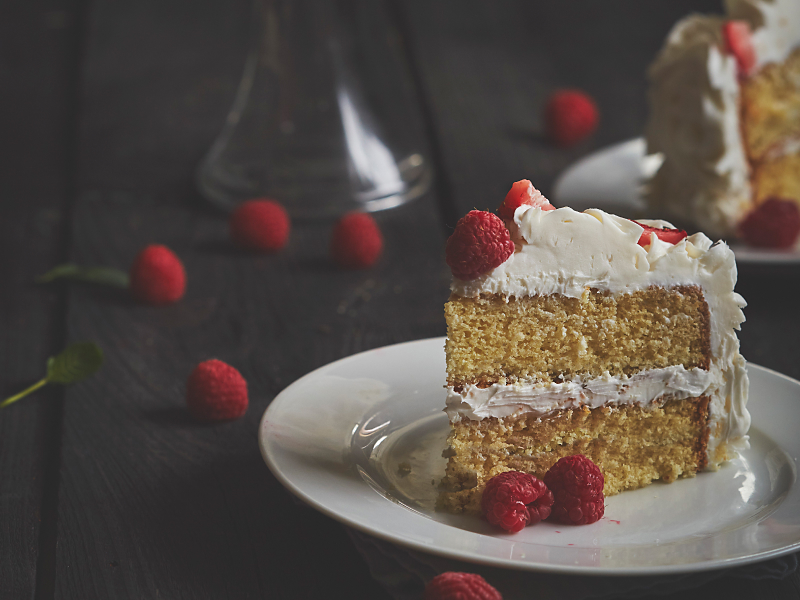 Vanilla butter cake on plate garnished with raspberries