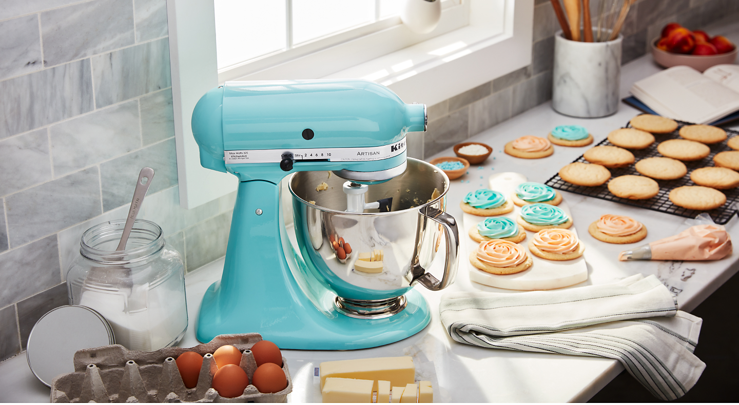 Bright blue KitchenAid® stand mixer next to decorated sugar cookies
